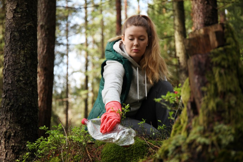 Nainen kerää roskia luonnosta.