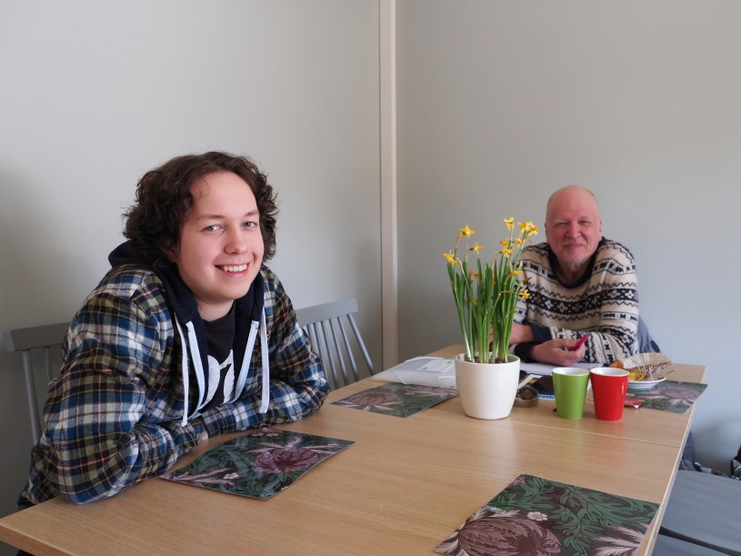 Kaksi miestä istuu pöydän äärellä kahvihuoneessa.