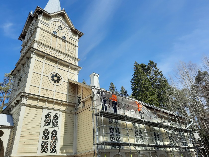 Vaalean puukirkon ympärillä on rakennustelineitä.