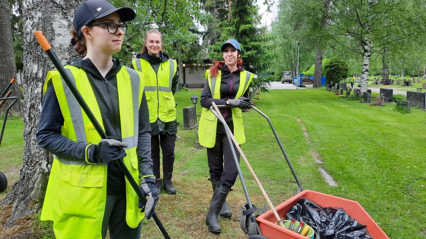 Kolme nuorta työntekijää hautausmaalla.