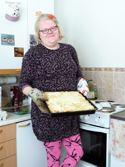 Sanna Ryhänen seisoo keittiössä raparperipiirakka kädessään