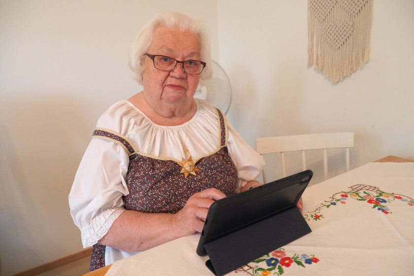 Nainen tietokoneen kanssa keittiönpöydän äärellä.