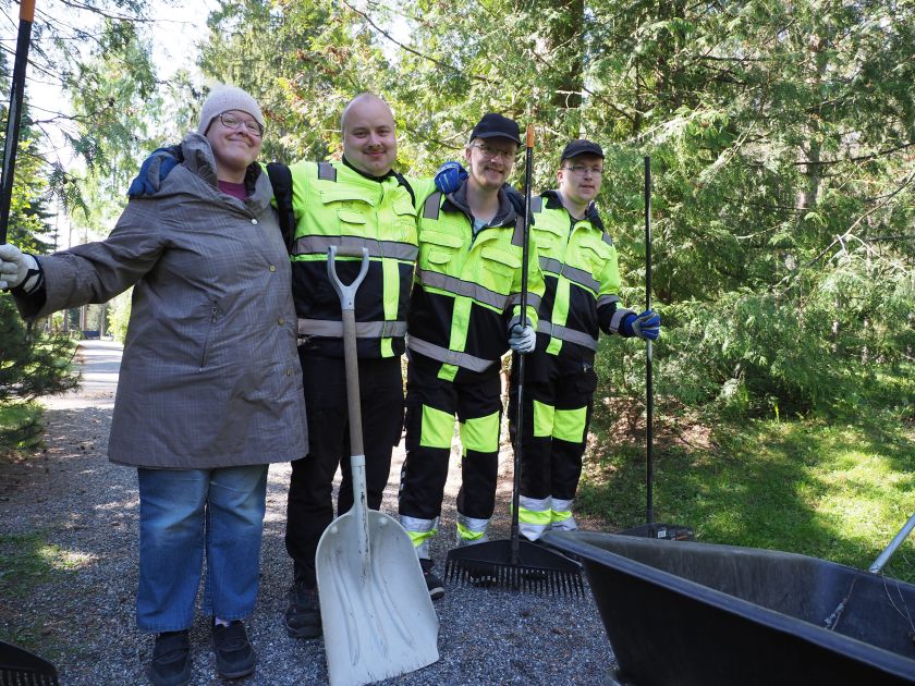 Neljä työntekijää työkaluineen hautausmaan alueella.