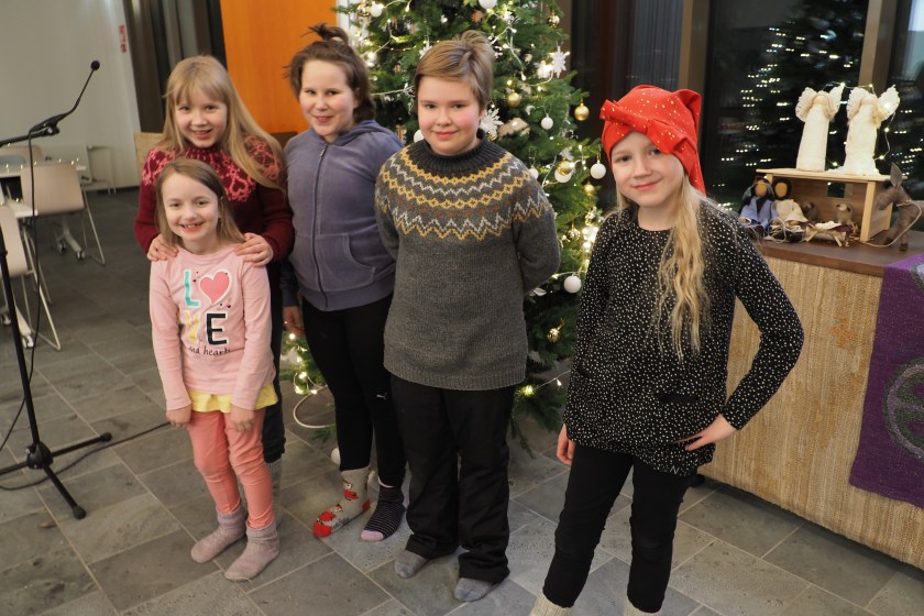 Viisi lapsikuoron lasta joulukuusen äärellä.